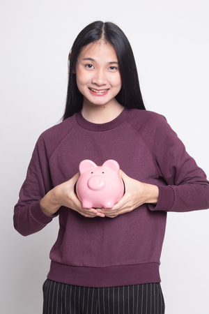 Young Asian woman with a pig coin bank on white backgroundの写真素材