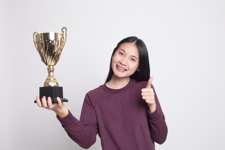Successful young asian woman holding a trophy show thumb up on white backgroundの写真素材