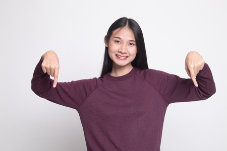 Beautiful young Asian woman point down to blank space on white backgroundの写真素材