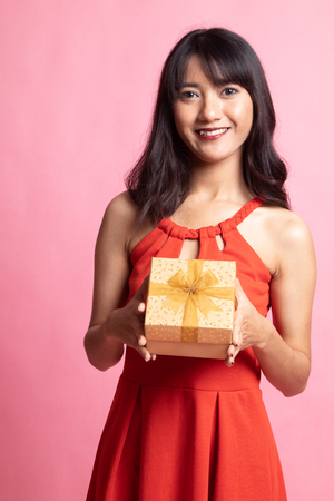 Young Asian woman with a gift box on pink backgroundの写真素材