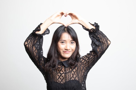 Young Asian woman gesturing heart hand sign on white backgroundの写真素材