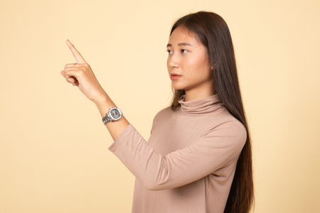 Asian woman touching the screen with her finger  on beige backgroundの写真素材