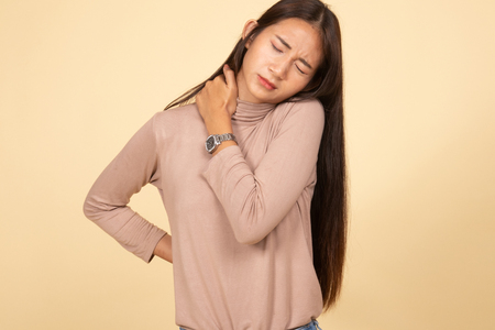 Young Asian woman got back pain  on beige backgroundの写真素材
