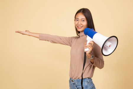 Beautiful young Asian woman announce with megaphone  on beige backgroundの写真素材