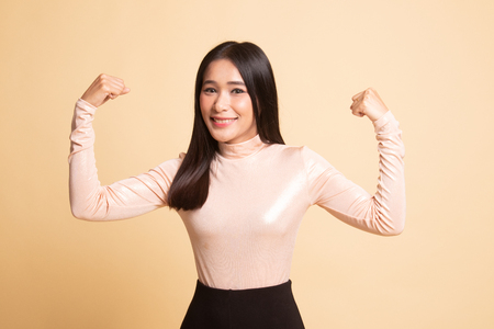 Beautiful young Asian woman flex bicep on  beige backgroundの写真素材