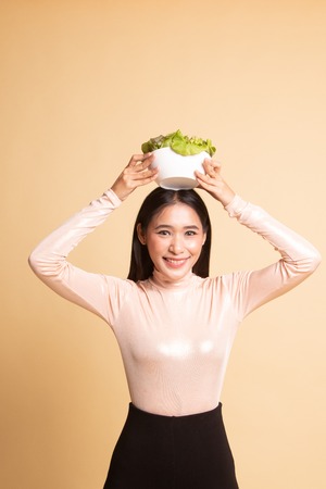 Healthy Asian woman with salad on  beige backgroundの写真素材