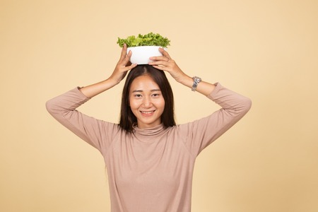 Healthy Asian woman with salad  on beige background