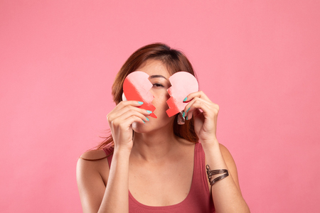 Beautiful young Asian woman with broken heart on pink backgroundの写真素材