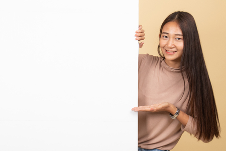 Young Asian woman present blank sign with palm hand  on beige backgroundの写真素材