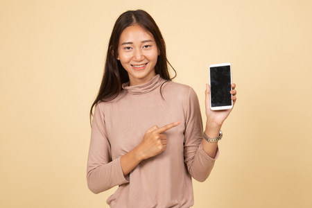 Young Asian woman point to mobile phone  on beige backgroundの写真素材
