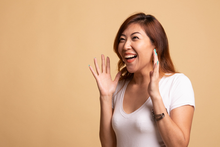 Young Asian woman is surprised and smile on beige background