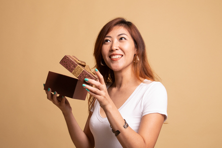 Young Asian woman open a gift box on beige backgroundの写真素材