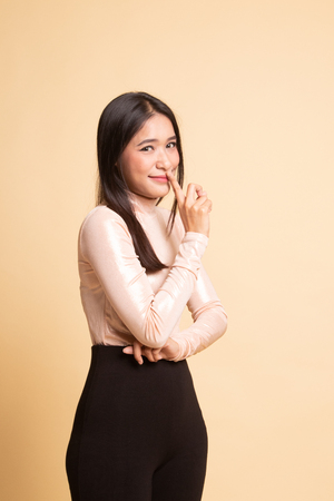 Asian girl show quite hand sign on  beige backgroundの写真素材