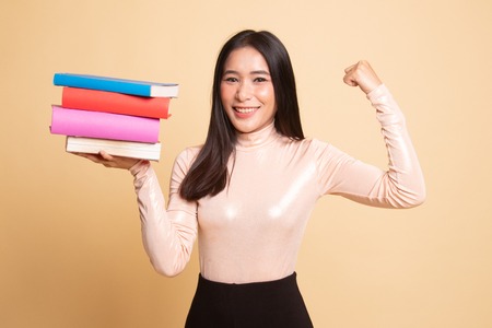 Young Asian woman studying  with may books on  beige background