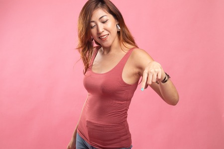 Beautiful young Asian woman point down to blank space on pink backgroundの写真素材