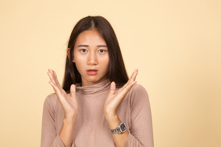Shocked young Asian woman  on beige backgroundの写真素材