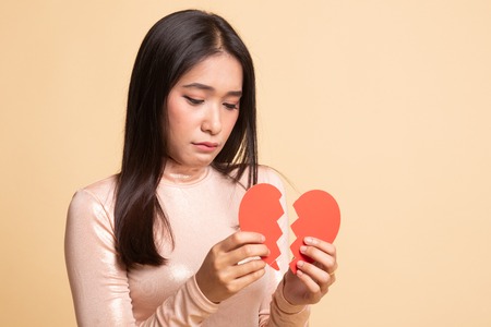 Beautiful young Asian woman with broken heart on  beige backgroundの写真素材