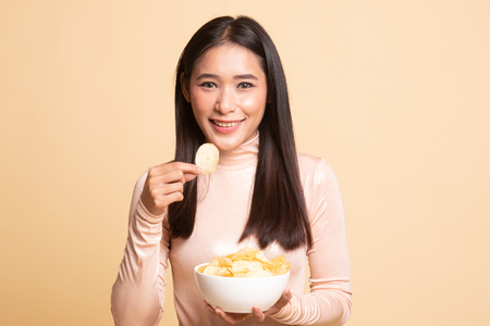 Young Asian woman eat potato chips on  beige backgroundの写真素材