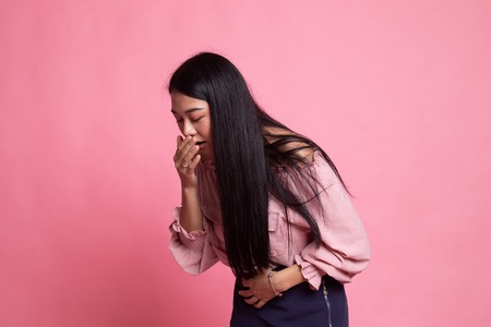 Young Asian woman got stomachache about to vomit on pink backgroundの写真素材