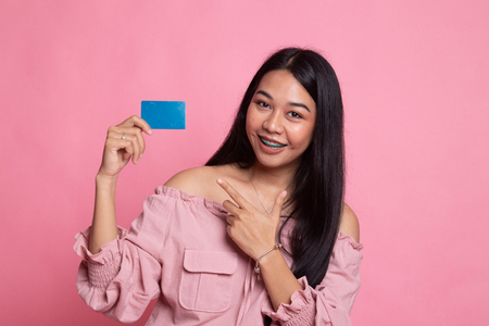Young Asian woman point to a blank card on pink backgroundの写真素材