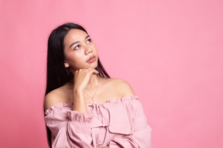 Serious  young Asian woman  look away on pink background