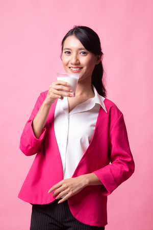 Healthy Asian woman drinking a glass of milk on pink backgroundの写真素材