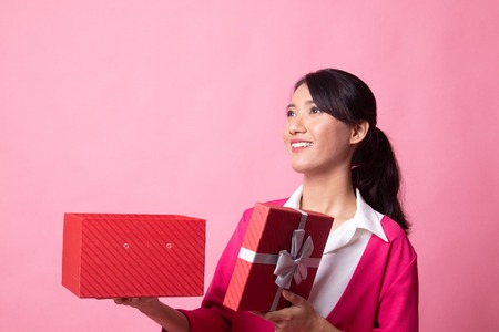 Young Asian woman open a gift box on pink backgroundの写真素材