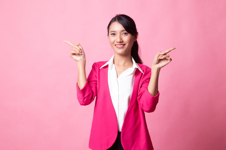 Young Asian woman point to left and right on pink backgroundの写真素材