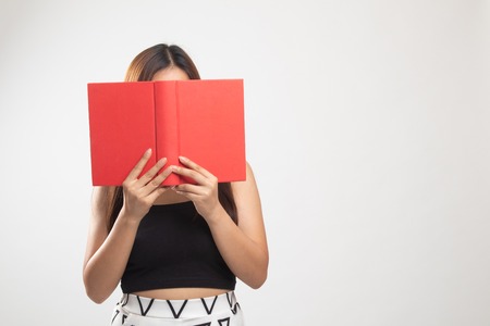 Young Asian woman with a book cover her face on white backgroundの写真素材