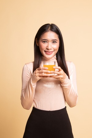 Young Asian woman drink orange juice on  beige backgroundの写真素材