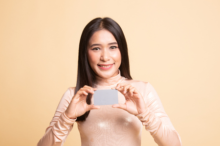 Young Asian woman smile with blank card on  beige backgroundの写真素材