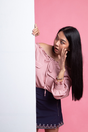 Excited young Asian woman with blank sign on pink backgroundの写真素材