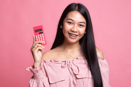 Asian woman smile with calculator on pink backgroundの写真素材