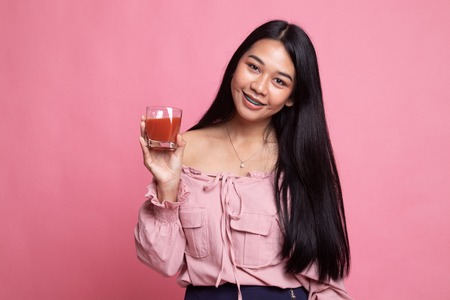 Young Asian woman drink tomato juice on pink backgroundの写真素材