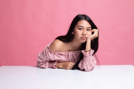 Asian girl is getting bore on pink backgroundの写真素材