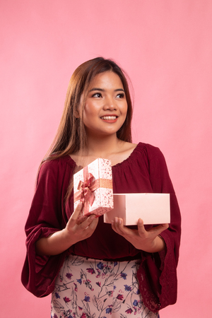 Young Asian woman open a gift box on pink backgroundの写真素材