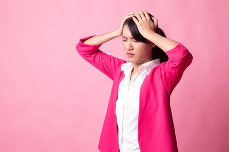 Stressed young Asian businesswoman scream out on pink backgroundの写真素材