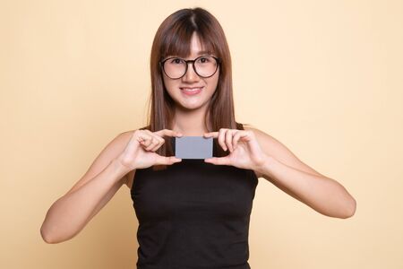 Young Asian woman smile with blank card  on beige backgroundの写真素材
