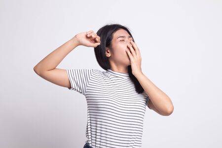Sleepy young Asian woman yawn on white backgroundの写真素材