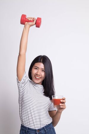 Young healthy Asian woman with dumbbell and  tomato juice on white backgroundの写真素材