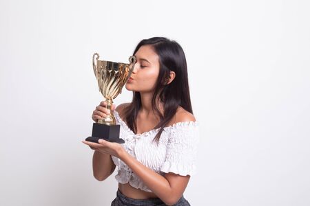 Successful young asian woman holding kissing a trophy on white backgroundの写真素材