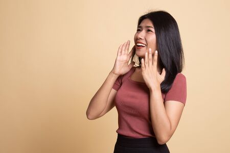Beautiful young Asian woman shocked  and look up on beige backgroundの写真素材