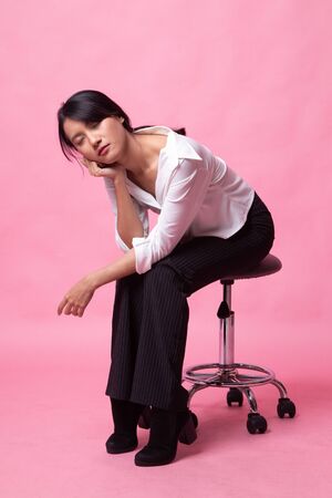 Full body of beautiful young asian woman sit on chair  on pink backgroundの写真素材