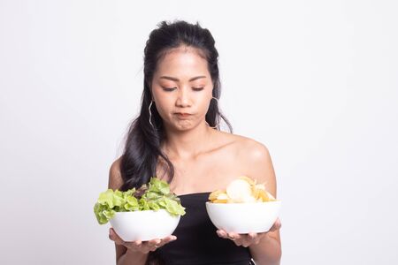 Young Asian woman with potato chips and salad on white backgroundの写真素材