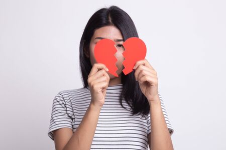 Beautiful young Asian woman with broken heart on white backgroundの写真素材
