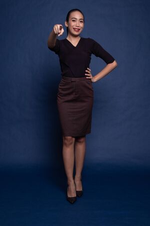 Full body of beautiful young asian woman pointing on blue backgroundの写真素材