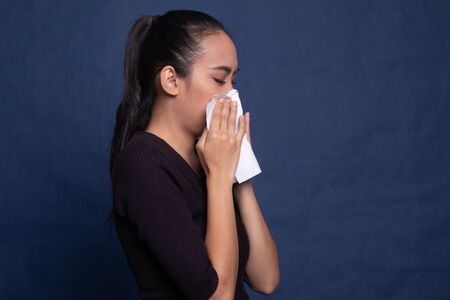 Young Asian woman got sick and flu on blue backgroundの写真素材