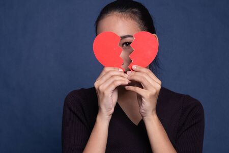 Beautiful young Asian woman with broken heart on blue backgroundの写真素材