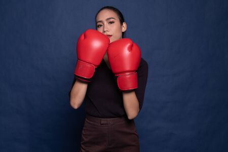 Young Asian woman with red boxing gloves on blue backgroundの写真素材
