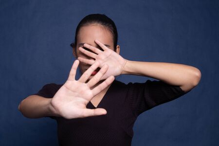 Young Asian woman hide her  face on blue backgroundの写真素材